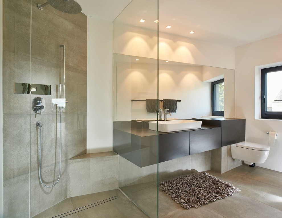 Duschbad With flächenbündigen Schrankfronten, schwarzen Schränken, offener Dusche, Wandtoilette mit Spülkasten, grauen Fliesen, weißer Wandfarbe, Aufsatzwaschbecken, grauem Boden and schwarzer Waschtischplatte in Stuttgart