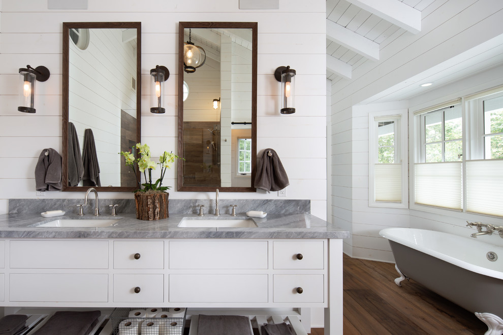 Design ideas for a country bathroom in Santa Barbara with white cabinets, a claw-foot tub, medium hardwood floors, an undermount sink, brown floor, grey benchtops and flat-panel cabinets.