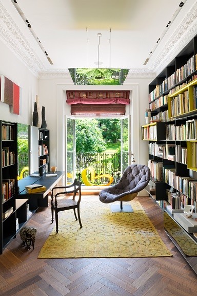 This is an example of a contemporary open concept living room in London with a library and white walls.