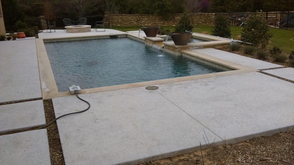 This is an example of a mid-sized contemporary backyard rectangular lap pool in Dallas with a hot tub and natural stone pavers.