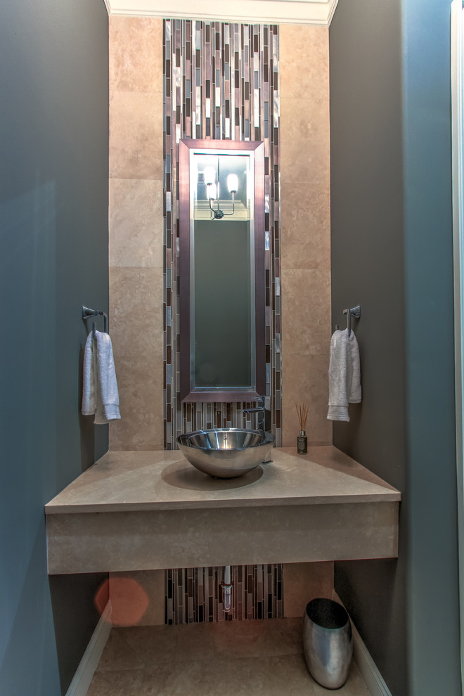 This is an example of a mid-sized transitional powder room in Atlanta with glass tile, travertine floors, a vessel sink, travertine benchtops, brown tile, multi-coloured tile, grey walls and brown floor.