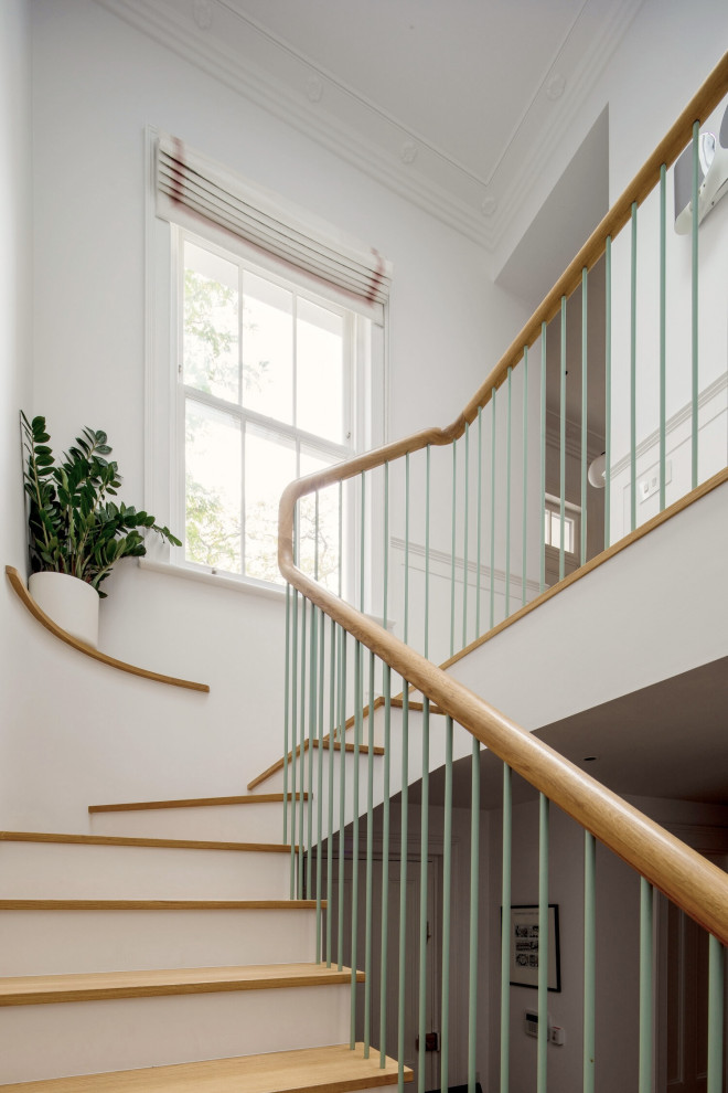 Photo of a large contemporary wood l-shaped staircase in London with painted wood risers, metal railing and panelled walls.