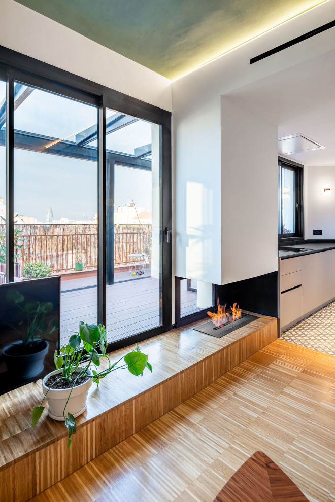Réalisation d'une petite salle de séjour design ouverte avec un sol en bois brun, une cheminée d'angle, un manteau de cheminée en métal et un sol marron.
