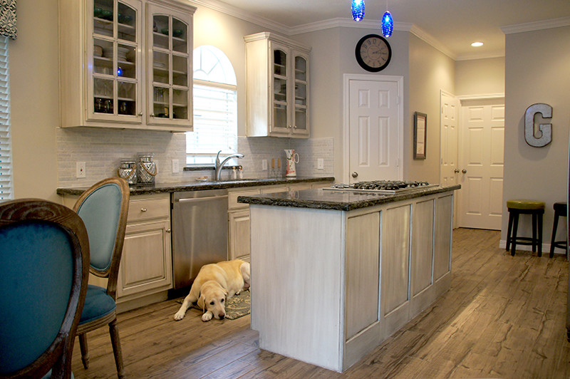 Mid-sized transitional galley porcelain tile eat-in kitchen photo in Houston with quartzite countertops, white backsplash, stone tile backsplash, stainless steel appliances, an island, a double-bowl sink, raised-panel cabinets and white cabinets