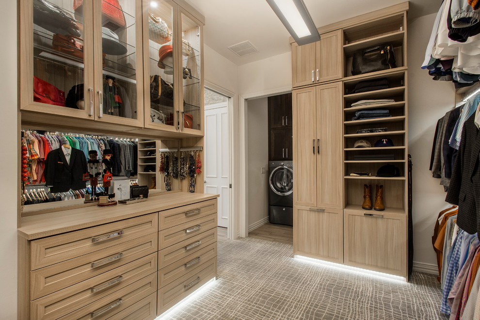 Photo of a large transitional gender-neutral dressing room in Dallas with light wood cabinets, carpet and grey floor.