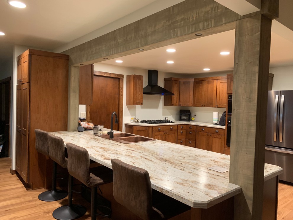 Example of a large mountain style brown floor eat-in kitchen design with a drop-in sink, flat-panel cabinets, laminate countertops, black appliances, white countertops and medium tone wood cabinets