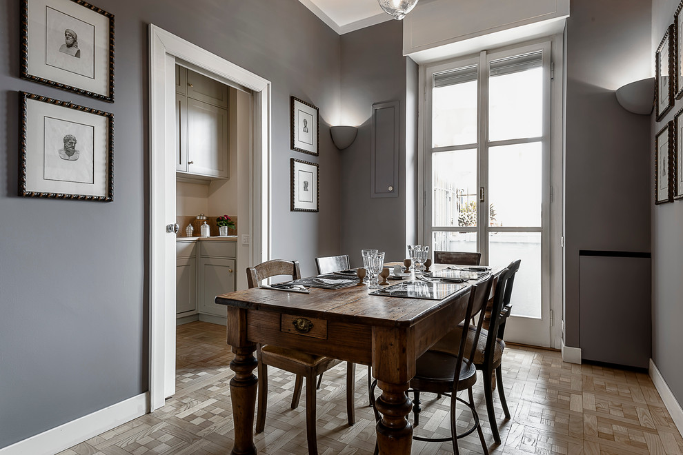 Mid-sized traditional separate dining room in Milan with grey walls, medium hardwood floors and a plaster fireplace surround.