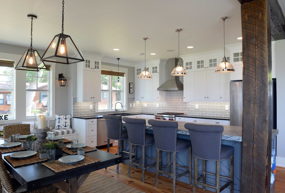 Eat-in kitchen - mid-sized transitional l-shaped light wood floor eat-in kitchen idea with shaker cabinets, white cabinets, granite countertops, gray backsplash, subway tile backsplash, stainless steel appliances, an island and an undermount sink