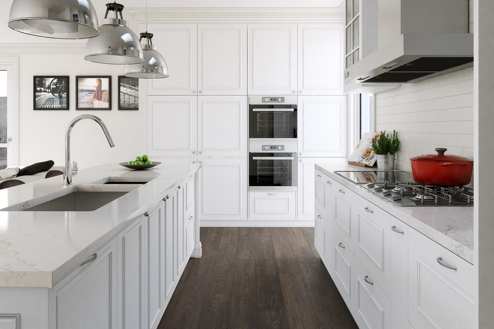 This is an example of a large traditional galley separate kitchen in Melbourne with an undermount sink, raised-panel cabinets, white cabinets, marble benchtops, white splashback, ceramic splashback, stainless steel appliances, with island and dark hardwood floors.