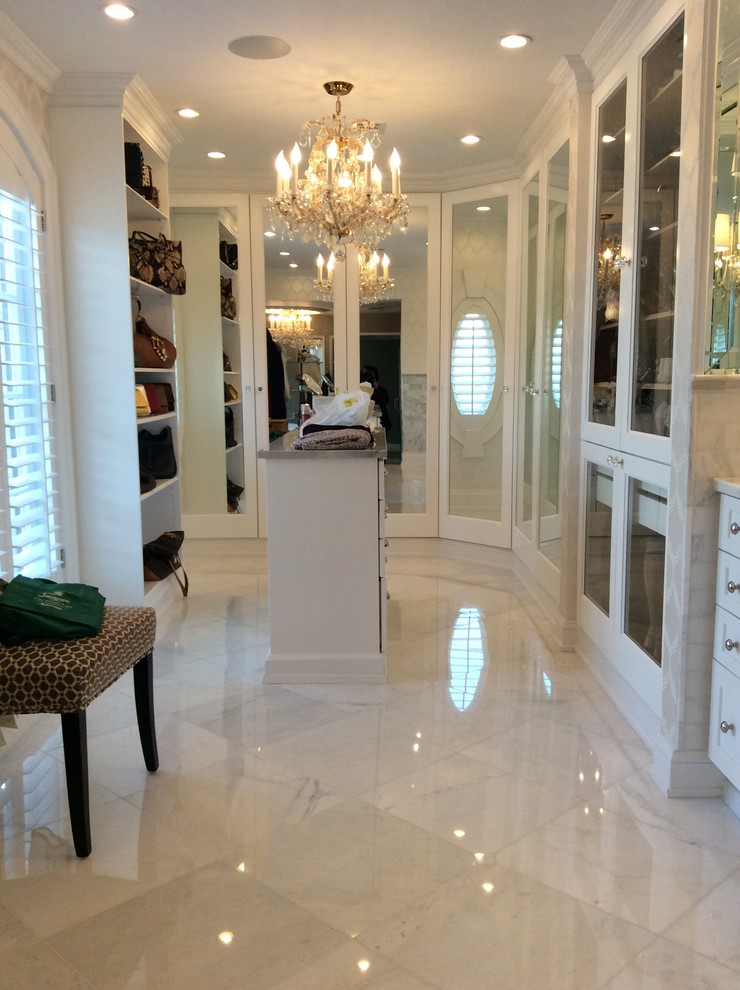 Photo of a mid-sized transitional women's dressing room in New York with shaker cabinets, white cabinets and marble floors.