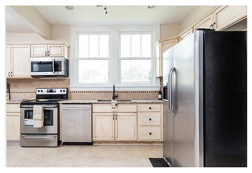 Mid-sized arts and crafts u-shaped eat-in kitchen in Indianapolis with an undermount sink, recessed-panel cabinets, distressed cabinets, granite benchtops, beige splashback, ceramic splashback, stainless steel appliances and ceramic floors.