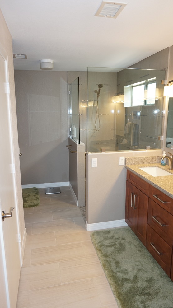 Photo of a large transitional 3/4 bathroom in Phoenix with an undermount sink, shaker cabinets, medium wood cabinets, granite benchtops, an alcove shower, a two-piece toilet, beige tile, pebble tile and beige walls.