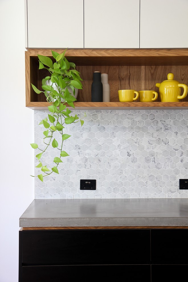 Inspiration for a mid-sized industrial galley kitchen in Brisbane with an integrated sink, concrete benchtops, grey splashback, stone tile splashback, light hardwood floors and with island.