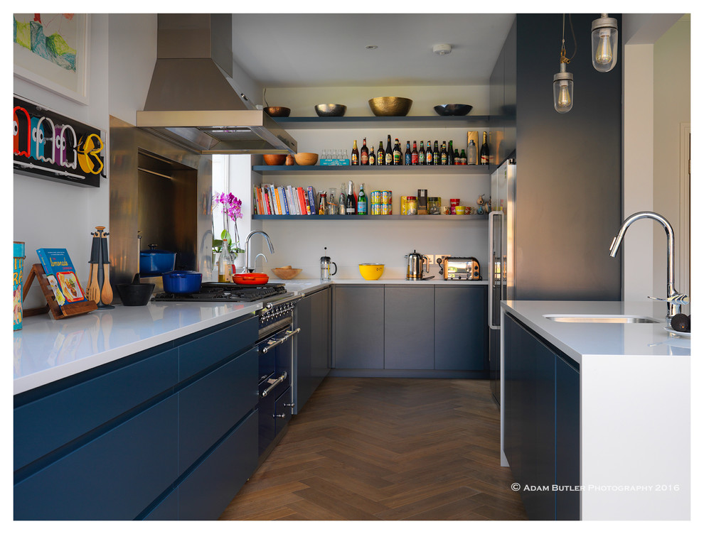 Modern open plan kitchen in London with a single-bowl sink, flat-panel cabinets, blue cabinets, soapstone benchtops, stainless steel appliances, light hardwood floors and with island.