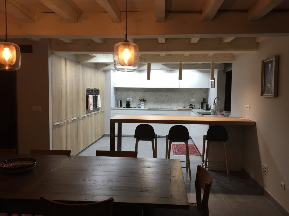 На фото: кухня среднего размера в стиле рустика с обеденным столом, фасадами с утопленной филенкой, светлыми деревянными фасадами, полуостровом и балками на потолке с
