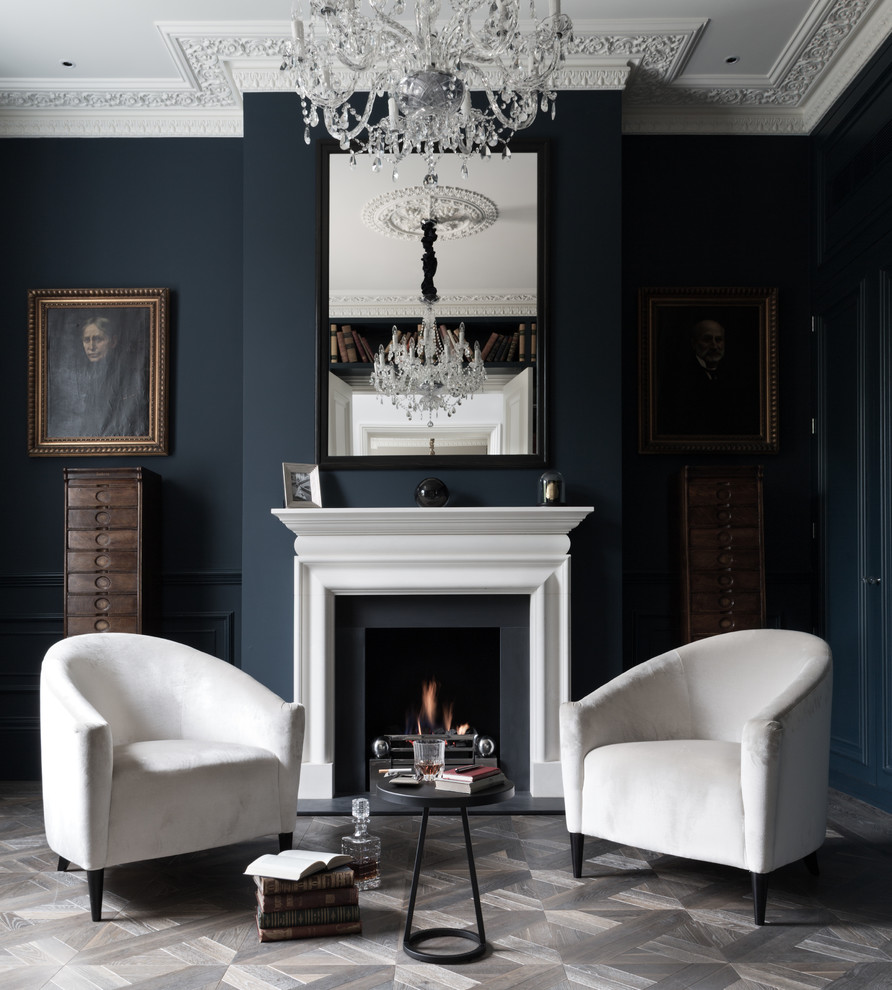 Photo of a mid-sized transitional formal enclosed living room in London with blue walls, a standard fireplace and grey floor.