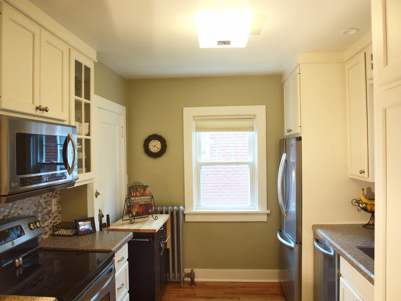 Transitional medium tone wood floor enclosed kitchen photo with an undermount sink, recessed-panel cabinets, white cabinets, quartz countertops, gray backsplash, stainless steel appliances and no island