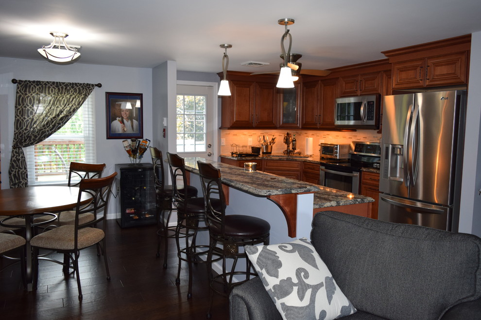 Example of a classic dark wood floor kitchen design with an undermount sink, beaded inset cabinets, medium tone wood cabinets, quartz countertops, beige backsplash, subway tile backsplash, stainless steel appliances and an island