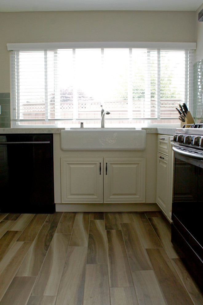 Photo of a mid-sized transitional u-shaped separate kitchen in San Francisco with a farmhouse sink, recessed-panel cabinets, yellow cabinets, quartz benchtops, green splashback, glass tile splashback, stainless steel appliances, porcelain floors, no island and multi-coloured floor.