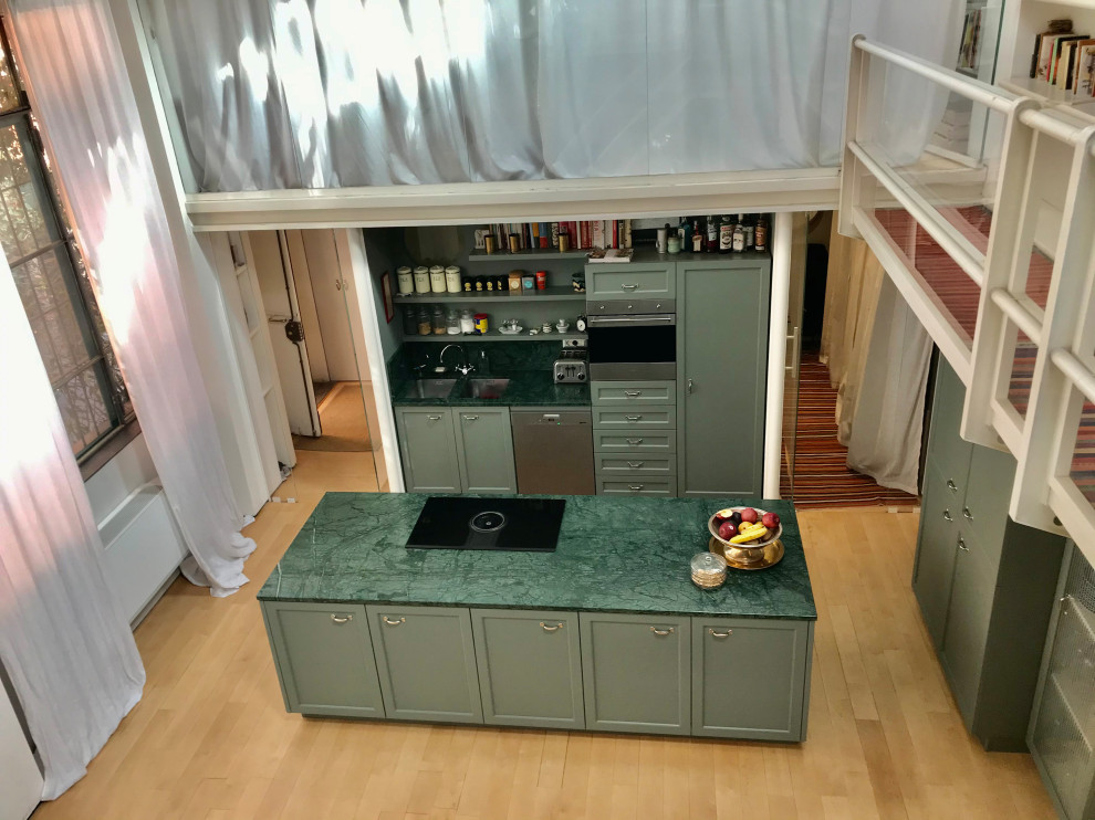 Modern inredning av ett stort grön grönt kök, med en integrerad diskho, luckor med infälld panel, gröna skåp, marmorbänkskiva, grönt stänkskydd, stänkskydd i marmor, rostfria vitvaror, ljust trägolv och en köksö