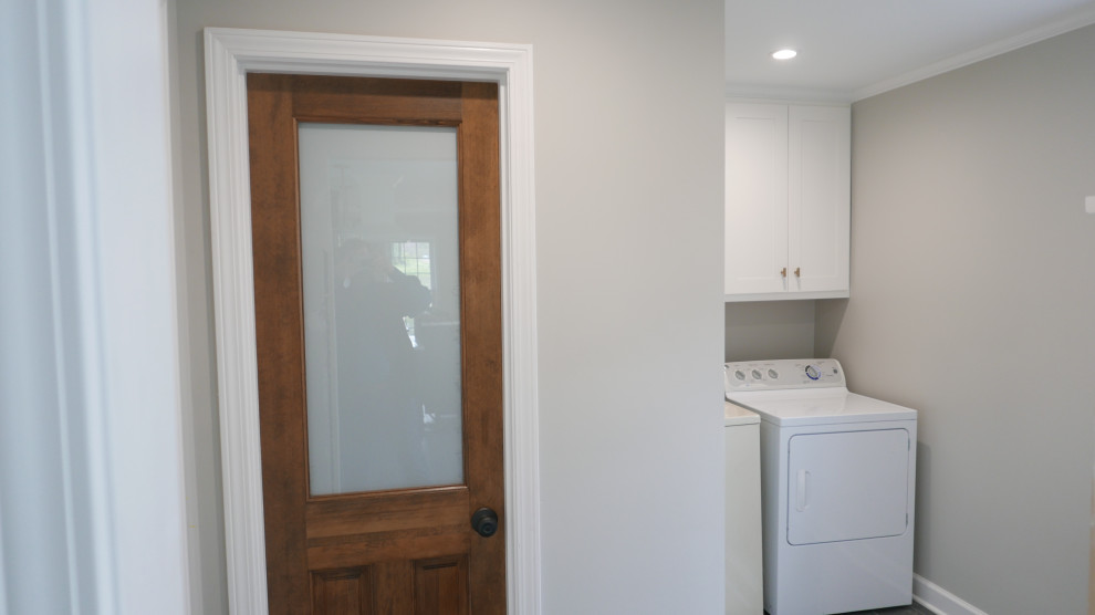 Mid-sized transitional u-shaped utility room in Other with shaker cabinets, white cabinets, grey walls, porcelain floors, a side-by-side washer and dryer and black floor.