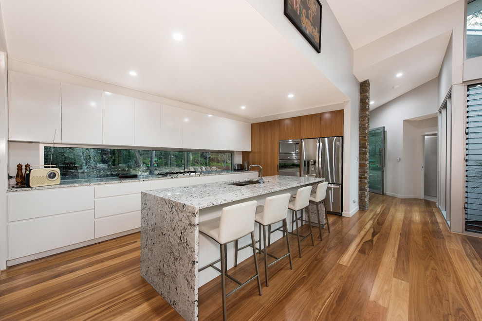 Transitional galley kitchen in Brisbane with an undermount sink, flat-panel cabinets, white cabinets, stainless steel appliances, dark hardwood floors and with island.