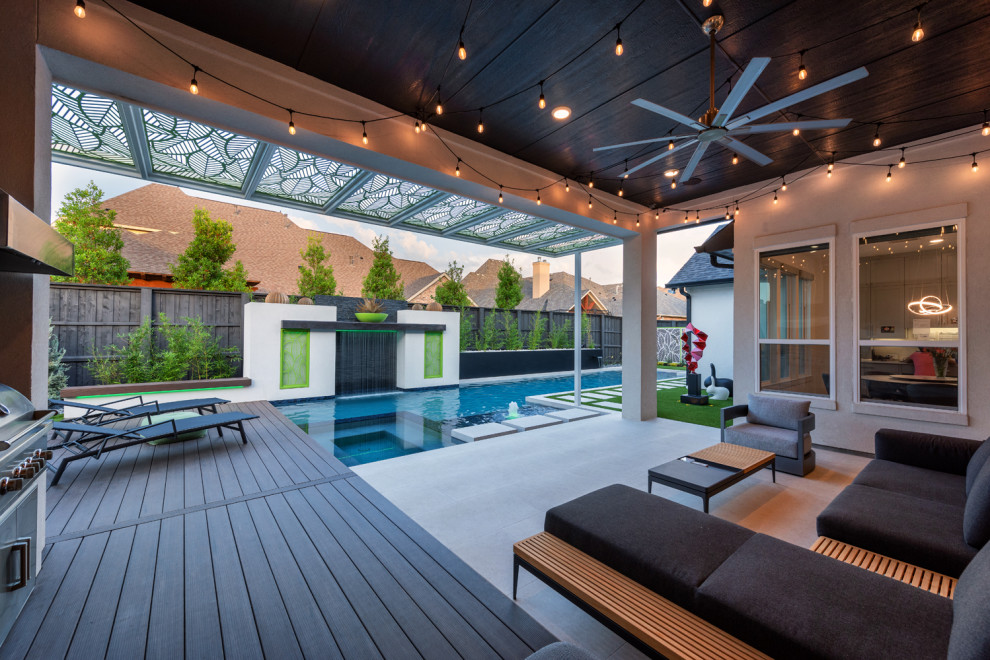 This is an example of a large modern backyard rectangular pool in Dallas with a water feature.