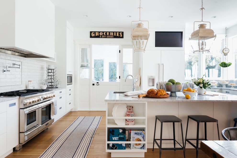 This is an example of a large country u-shaped eat-in kitchen in Vancouver with an undermount sink, flat-panel cabinets, white cabinets, marble benchtops, white splashback, subway tile splashback, panelled appliances, with island, white benchtop, medium hardwood floors and beige floor.