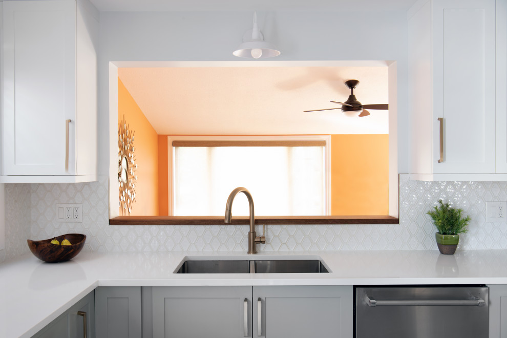 Example of a mid-sized transitional l-shaped ceramic tile kitchen design in Ottawa with a double-bowl sink, shaker cabinets, quartz countertops, white backsplash, stainless steel appliances, a peninsula and white countertops
