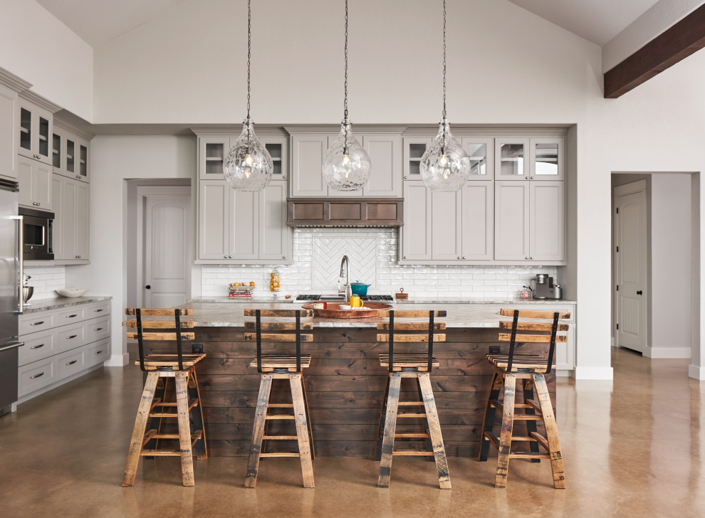 Kitchen - transitional concrete floor and brown floor kitchen idea with shaker cabinets, gray cabinets, white backsplash, subway tile backsplash, stainless steel appliances, an island and gray countertops