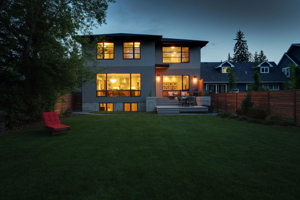 Inspiration for a large transitional two-story stucco gray home design remodel in Calgary with a hip roof and a shingle roof