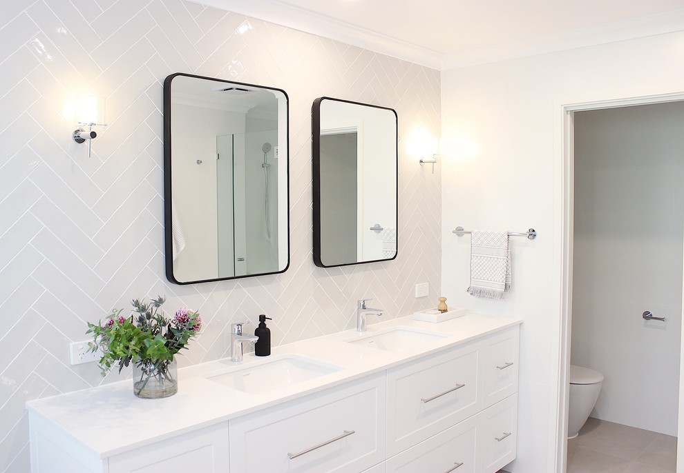 Design ideas for a mid-sized contemporary master bathroom in Perth with recessed-panel cabinets, white cabinets, a freestanding tub, a one-piece toilet, white tile, subway tile, white walls, ceramic floors, an undermount sink, engineered quartz benchtops and white benchtops.