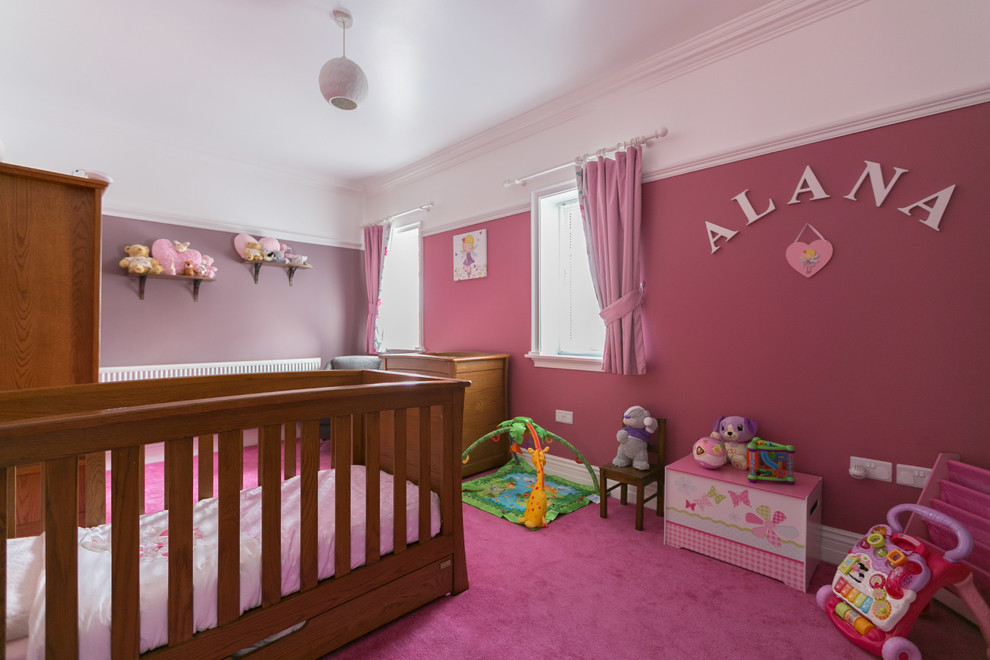 Mid-sized modern nursery in Other with pink walls and carpet for girls.
