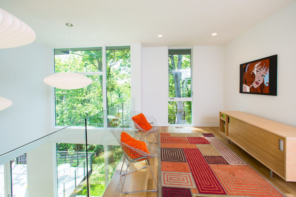 This is an example of a mid-sized contemporary loft-style family room in DC Metro with white walls, medium hardwood floors, no fireplace, a wall-mounted tv and brown floor.