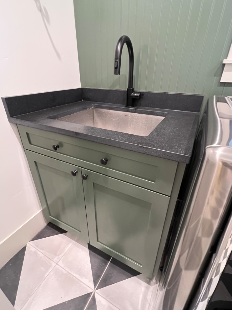 This is an example of a medium sized traditional separated utility room in Other with a submerged sink, flat-panel cabinets, green cabinets, engineered stone countertops, green splashback, wood splashback, beige walls, ceramic flooring, a side by side washer and dryer and black worktops.
