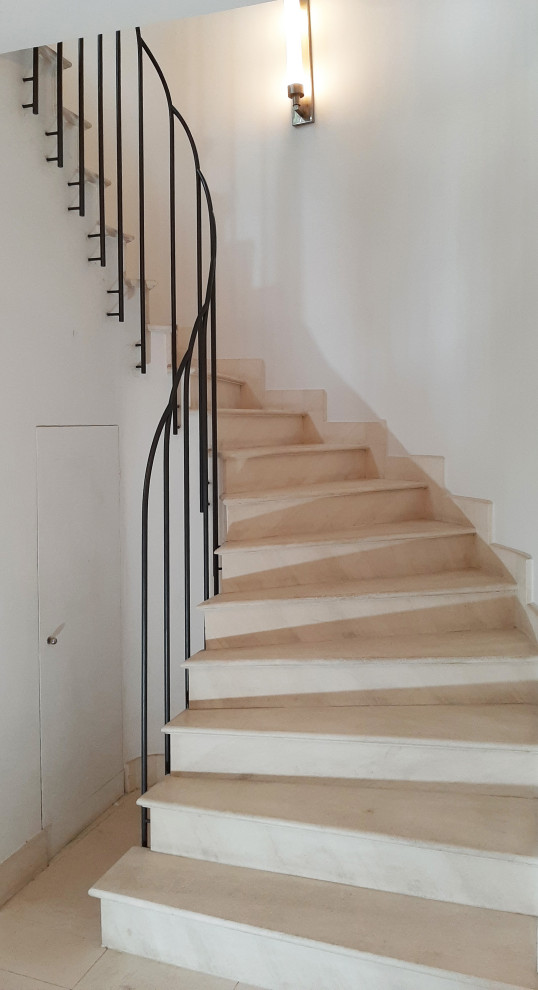 Diseño de escalera curva actual de tamaño medio con escalones de mármol, contrahuellas de mármol, barandilla de metal y papel pintado