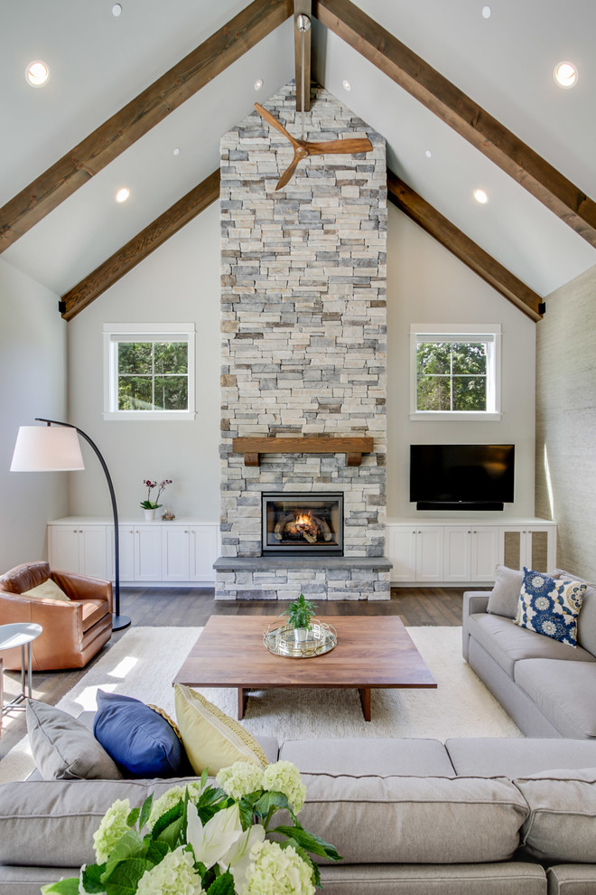 Large arts and crafts open concept family room in Seattle with grey walls, dark hardwood floors, a standard fireplace, a stone fireplace surround, a wall-mounted tv and brown floor.