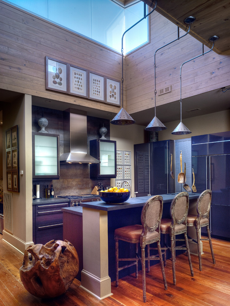Photo of an eclectic l-shaped kitchen in New Orleans with flat-panel cabinets and panelled appliances.