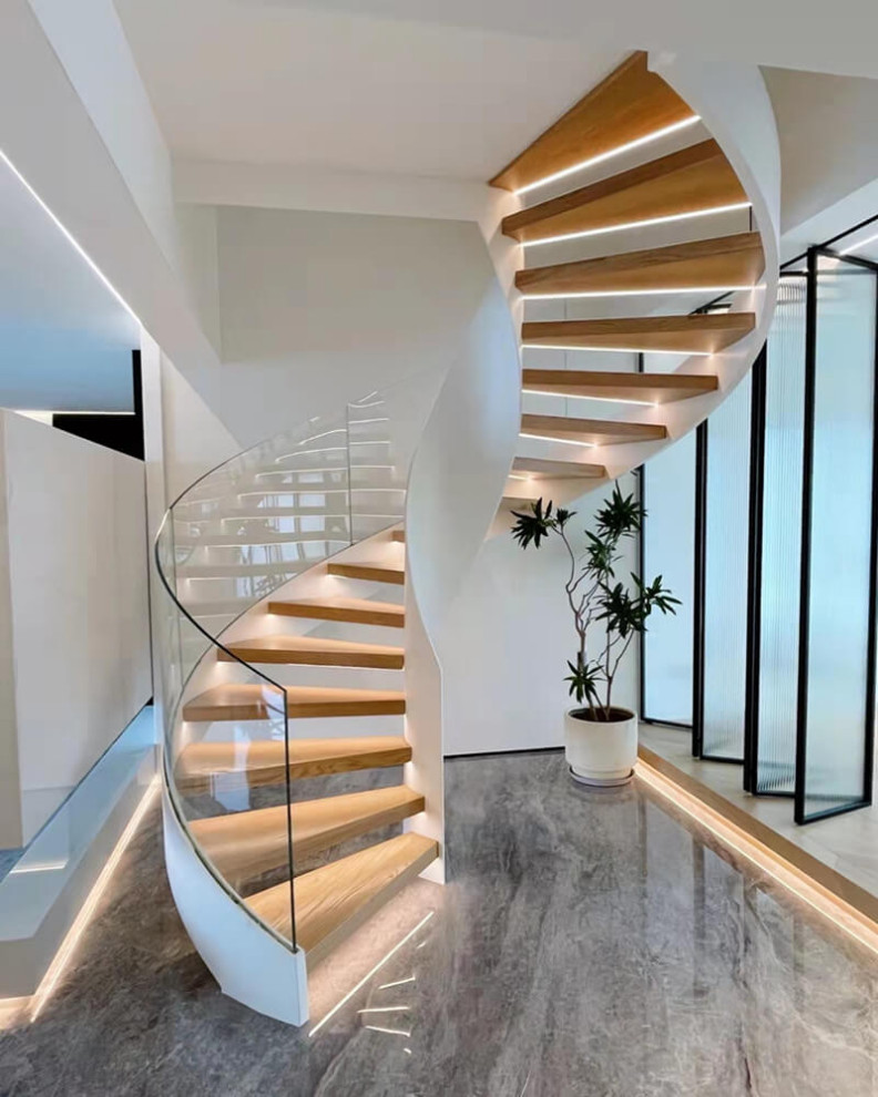 This is an example of a mid-sized modern wood curved staircase in Other with open risers, glass railing and brick walls.