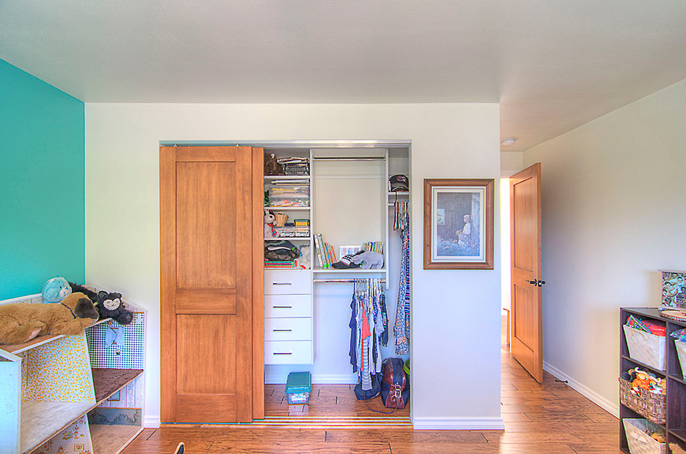 This is an example of a mid-sized traditional gender-neutral built-in wardrobe in Seattle with flat-panel cabinets, white cabinets and medium hardwood floors.