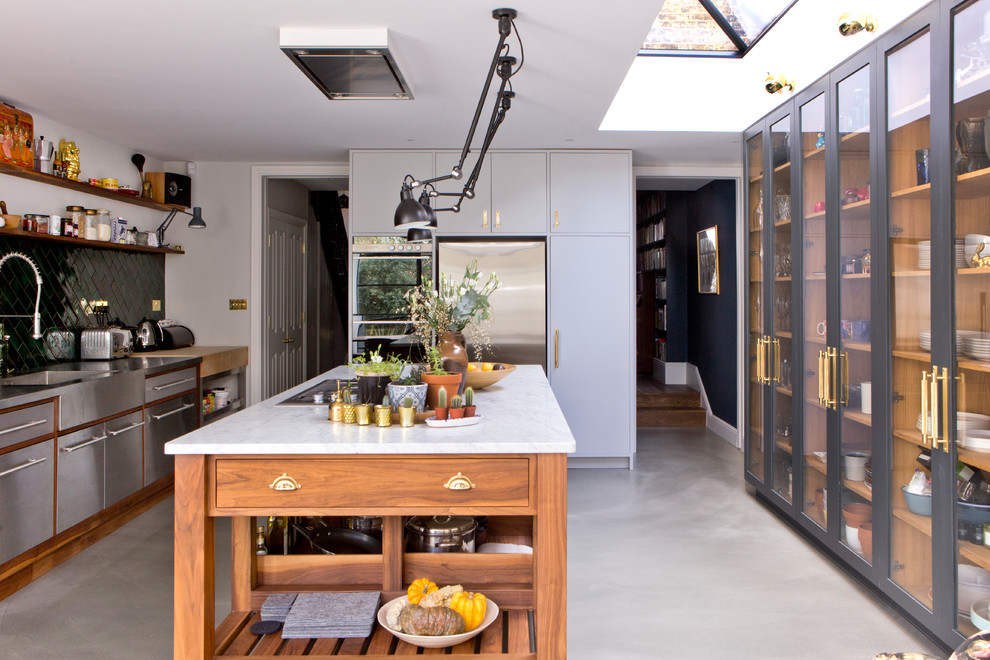 Inspiration for a contemporary galley open plan kitchen in London with an integrated sink, glass-front cabinets, black cabinets, marble benchtops, white splashback, subway tile splashback, stainless steel appliances, concrete floors, with island and grey floor.