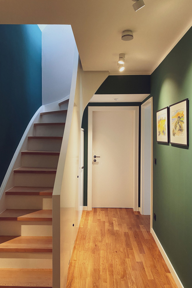 Exemple d'un escalier courbe tendance de taille moyenne avec des marches en bois, des contremarches en bois, un garde-corps en bois et du papier peint.
