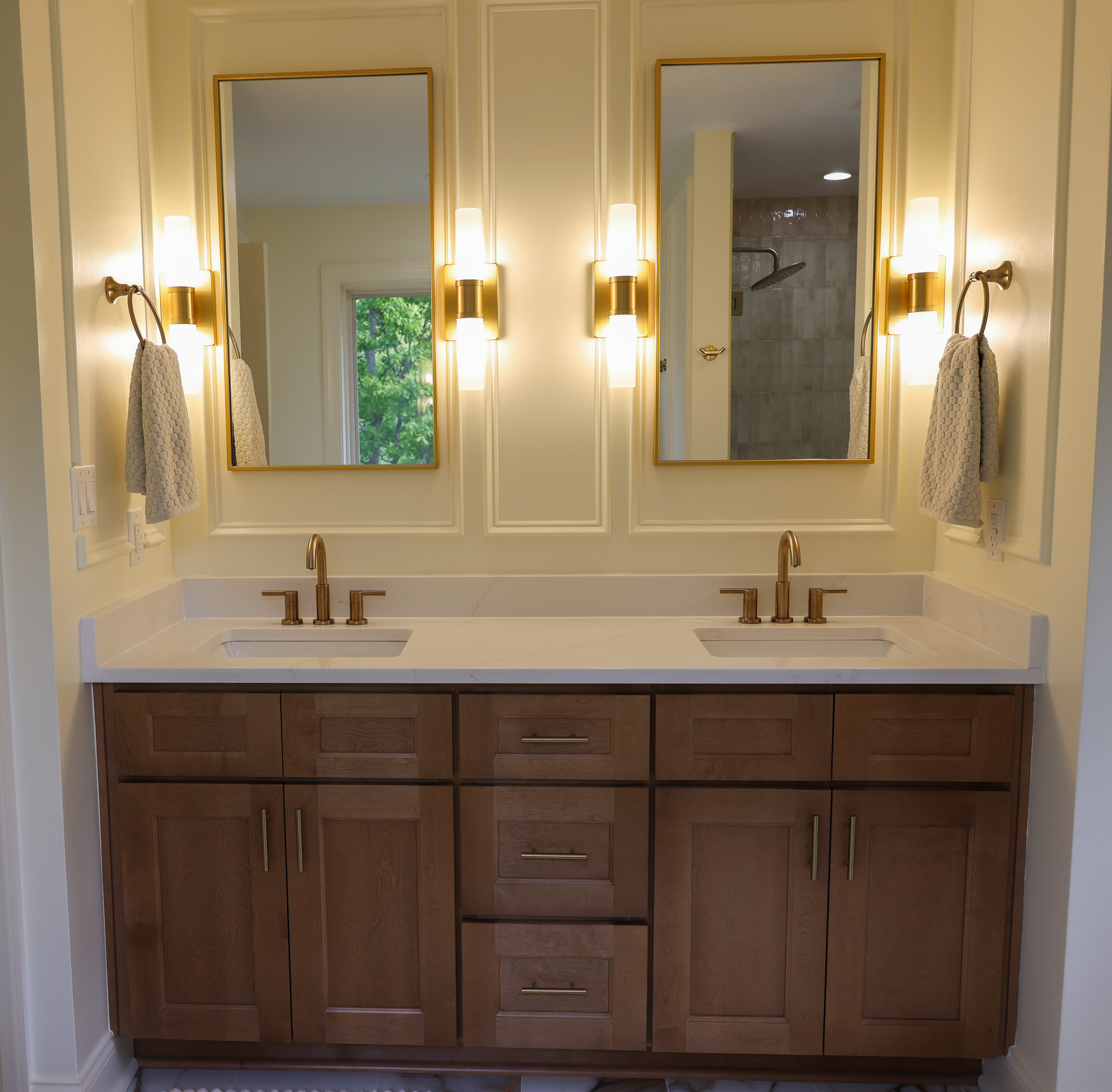 Custom double vanity featuring quartzite countertops, gold fixtures, decorative mirrors, designer lighting, and detailed trim work.
