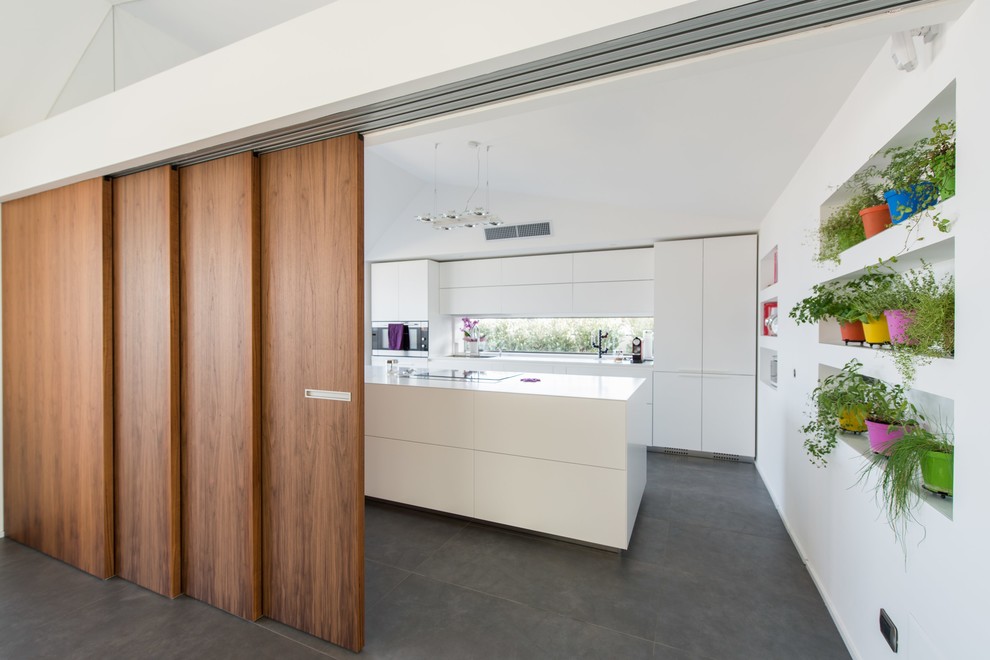 This is an example of an expansive contemporary galley kitchen in Catania-Palermo with flat-panel cabinets, white cabinets, white appliances and with island.