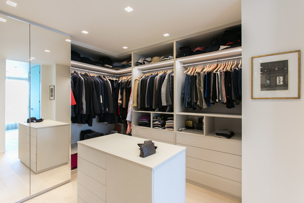 Photo of a large contemporary gender-neutral dressing room in Milan with flat-panel cabinets, white cabinets, light hardwood floors and beige floor.