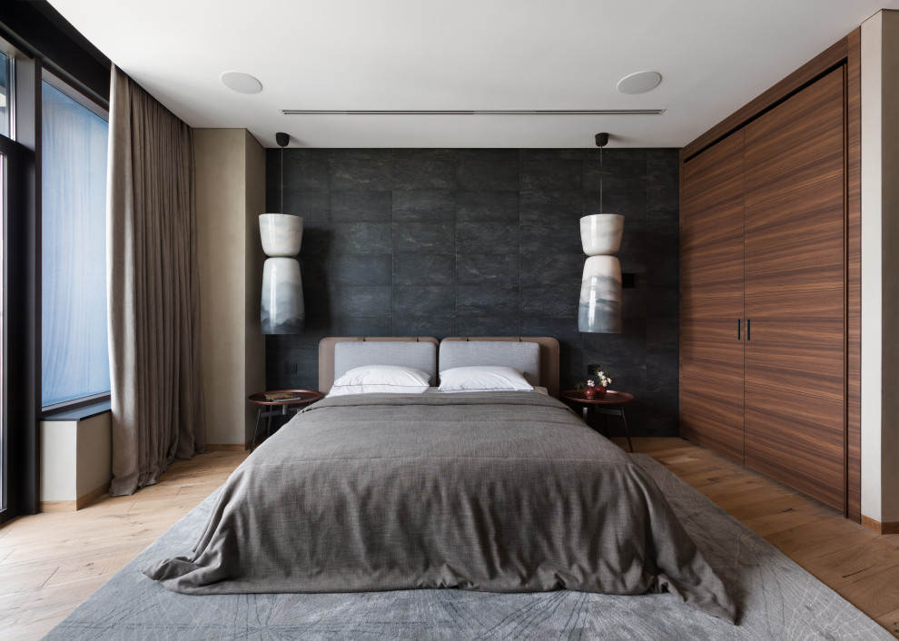 На фото: гостевая, серо-белая спальня среднего размера, (комната для гостей) в стиле лофт с бежевыми стенами, паркетным полом среднего тона, коричневым полом, панелями на стенах и акцентной стеной