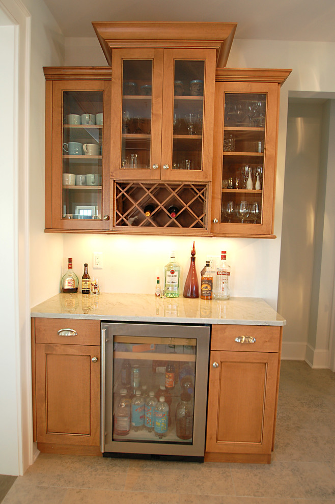 Photo of a mid-sized traditional u-shaped home bar in New York with an undermount sink, recessed-panel cabinets, medium wood cabinets, marble benchtops, white splashback, subway tile splashback and ceramic floors.