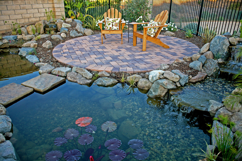 Inspiration for a small country backyard patio in Los Angeles with a water feature, concrete pavers and no cover.