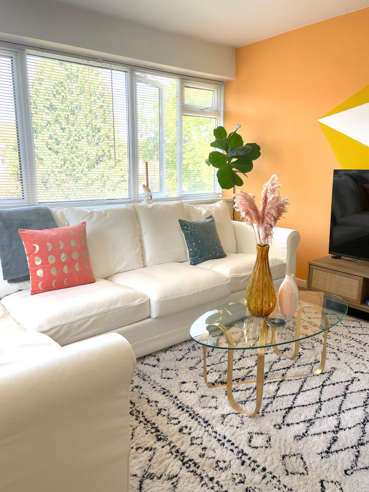 На фото: открытая гостиная комната среднего размера в современном стиле с разноцветными стенами, полом из ламината, отдельно стоящим телевизором, коричневым полом и акцентной стеной с