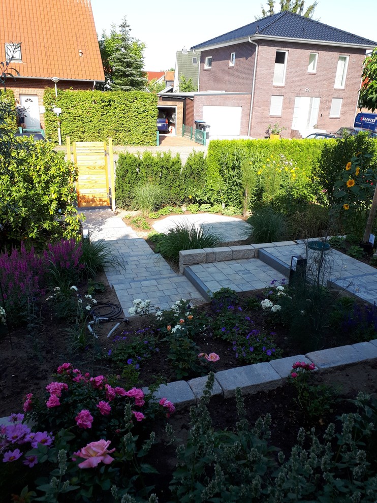 Kleiner Mediterraner Garten neben dem Haus mit Gehweg, direkter Sonneneinstrahlung und Betonboden in Hamburg